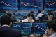 Stock traders on a busy trading floor surrounded by monitors filled with stock price charts and graphs.